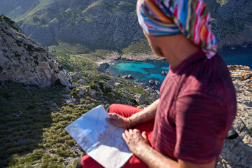 Active traveling man with map on rocky cliff