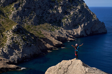 Man standing on rocky cliff and spreading arms