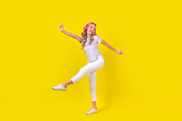 Fototapeta na wymiar Full length photo of positive woman dressed purple t-shirt listen energetic playlist in headphones isolated on yellow color background