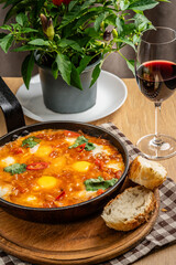 Traditional oriental cuisine. Arabic dish Shakshuka. Turkish breakfast, fried eggs, tomato sauce, peppers, cilantro and 2 pieces of baguette.