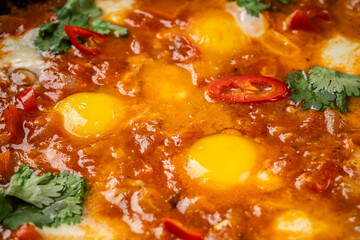 Traditional oriental cuisine. Arabic dish Shakshuka. Turkish breakfast, fried eggs, tomato sauce, peppers, cilantro and 2 pieces of baguette.