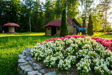 Park z drzewami liściastymi, pięknymi trawnikami, klombami kolorowych kwiatów i alejkami. Lato na Śląsku w Polsce, Rogów gmina Gorzyce. © Franciszek