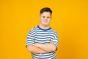 Smiling young man with cerebral palsy in glasses in a striped t-shirt on a yellow background. World...
