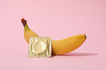 Condom with banana on a pink background
