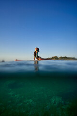 Unrecognizable woman practicing yoga in Cobra pose on SUP board