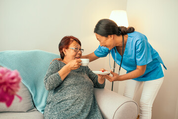 Cropped shot of seniors enjoying life in a retirement home. Happy patient is holding caregiver for a hand while spending time together. Elderly woman in nursing home and nurse.