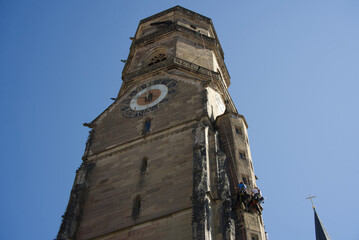 Two industrial climbers work on the south tower of the Striftskirche in Stuttgart