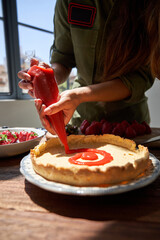 Faceless woman decorating cake with strawberry