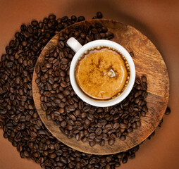Hot coffee cup and coffee beans on brown background