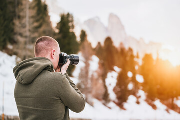 Photographer with a camera taking a picture of the snow mountains against blue sky in the Alps....