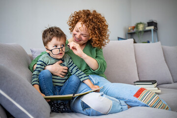 Mother and son in licing room spend some quality time. Mom and little kid son read book. Mom...