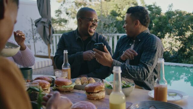 Two Men Laughing at A Cell Phone at an Outdoor lunch