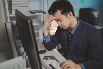 Asian male businessman working in the room. Startup company employees are working in the office at night, overtime, busy work, hard work. Overtime concept.