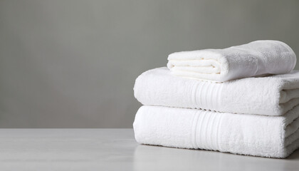Stack of clean soft white towels on table against light grey background. Space for text