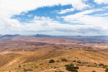 Desertic landscape of the interior of Fuerteventura island. Rocky hills with white sand. Sky with big white clouds. Sunny day Fuerteventura, Canary Islands, Spain.