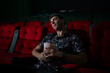 Man falls asleep while watching movie in cinema and popcorn in hand, Movie lacking interesting and boring.