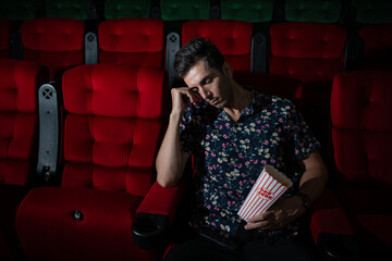 Man falls asleep while watching movie in cinema and popcorn in hand, Movie lacking interesting and boring.