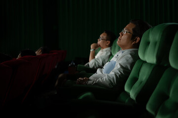 Fototapeta na wymiar Young couple watching movie in cinema, sitting on the green seats.