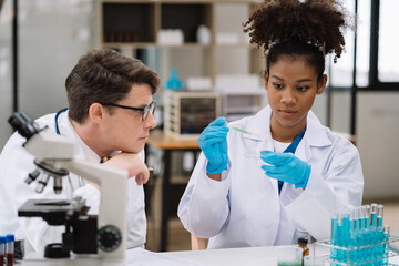 Team of biochemical research scientists working with a microscope for vaccine development in...