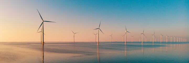 Windmill park with clouds and a blue sky, windmill park in the ocean aerial view with wind turbine Flevoland Netherlands Ijsselmeer. Green Energy production in the Netherlands on a sunny day - obrazy, fototapety, plakaty