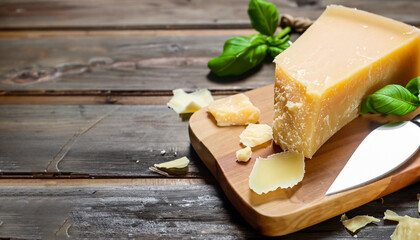 Delicious parmesan cheese with basil and knife on wooden table