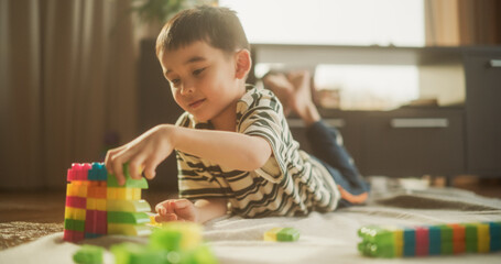 Portrait of Cute Male Asian Child Playing with Colourful Building Blocks in his Room During the Day. Creative and Focused Little Boy Using Logic and Skills to Make a Toy House. Happy Childhood.