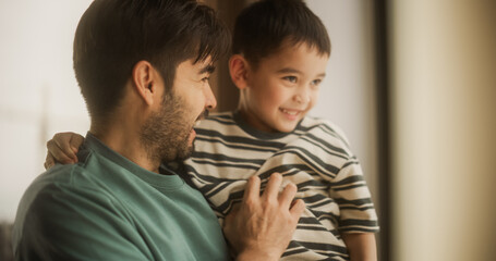 Portrait of Fatherly Love: A Young Father Holding His Male Child in His Arms as He Plays and...