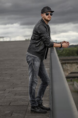 Junger Mann mit Sonnenbrille und Lederjacke seitlich