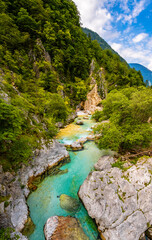 Fototapeta na wymiar Idyllic scenery at Soca or Isonzo river (Emerald River) in Slovenia is a wild alpine river with crystal clear water and turquoise green color with rapids and waterfalls. Seen from a suspension bridge.
