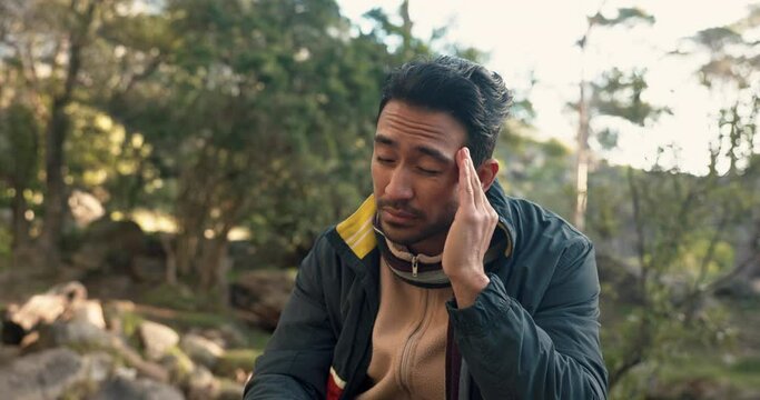 Hiking, fitness and asian man with headache, stress or dehydration in a forest with vertigo crisis. Hiker, accident and Japanese backpacker with migraine, dizzy or brain fog in a jungle with problem