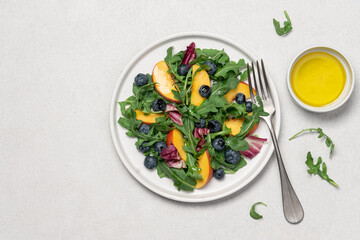 Peach arugula blueberry salad in plate on white background. Delicious fruit salad