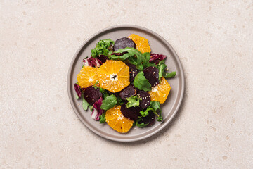 Seasonal vitamin salad orange beetroot and arugula in plate on light background. Diet, healthy eating concept