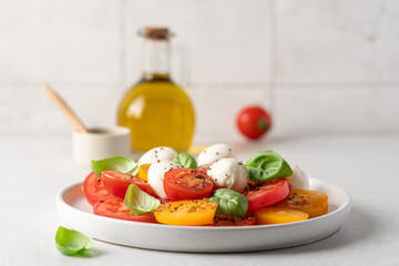 Appetizing Italian caprese salad. Tomatoes mozzarella basil salad close-up view on white background