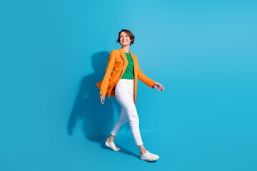Full body size photo of walking businesswoman young age looking empty space elegant style formal outfit isolated on blue color background