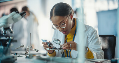Portrait of Black Female Lab Specialist Carefully Soldering a Circuit Board in a Manufacturing...