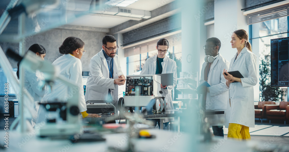 Poster Diverse Team of Industrial Robotics Specialists Gathered Around a Table With a Mobile Robot. Engineers In Lab Coats Discussing an Automated AI Robotic Delivery Assistant, Using Laptop and Tablet