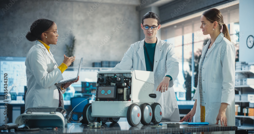Poster Team of Industrial Specialists Working on Mobile Robot, Using Laptop. Young Male and Female Engineers in a Lab Discussing Automated AI Robotic Delivery Assistant, Brainstorming Improvement Ideas