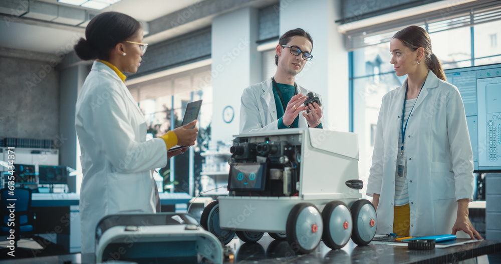 Fototapete Diverse Team of Industrial Specialists Working on Remotely Controlled Robot, Using a Laptop. Young Male and Female Engineers Discussing an Autonomous AI Delivery Assistant Prototype, Brainstorming