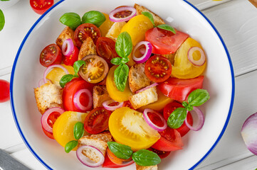 traditional Italian Panzanella salad with tomatoes, onion, fresh basil and bread. Vegetarian dish. top view
