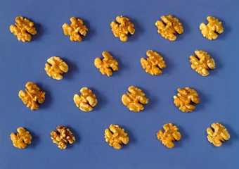 Foto op Plexiglas fresh walnuts, layed out in straight rows, blue background © Kirsten Hinte