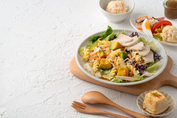 Fresh avocado lettuce salad bowl with chicken meat in a plate on white table background.