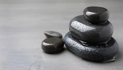 Wet spa stones on grey background. Space for text