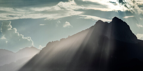 voluminous grazing light beams over the crest of the hahnenkamm mountains at sunset after a thunderstorm
