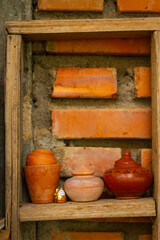 Miniature pottery kitchen utensils, handmade works arranged on the wall in the orange color.