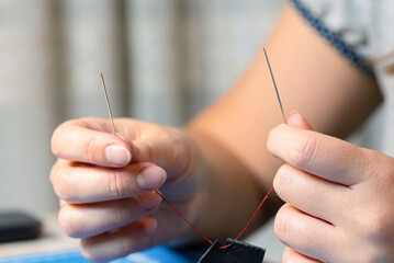 Woman holding in hand a stitching needles with the waxed thread close up. Leather craft concept.