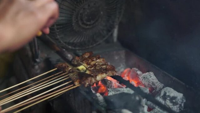 Portrait of a seller making rabbit satay to be grilled with charcoal, Indonesian culinary.