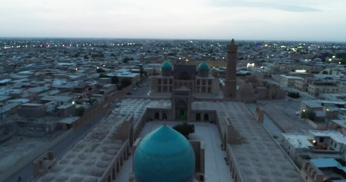 The drone flies at dawn over the old Bukhara and the memorial famous Kalyan Poi Kalon complex and Poi Kalon Minaret, Poi Kalan or Po-i-Kalyan and Mir Arab Madrasah