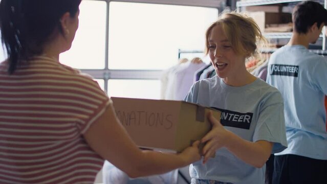 Female charity worker receiving box of donations from member of public - shot in slow motion