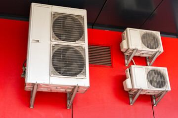 Air conditioners, compressors for air cooling hanging on street on red background
