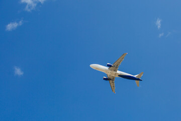 White- blue passenger airplane flying in the sky amazing clouds in the background